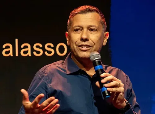 Rafael Galasso ao microfone em um palco escuro