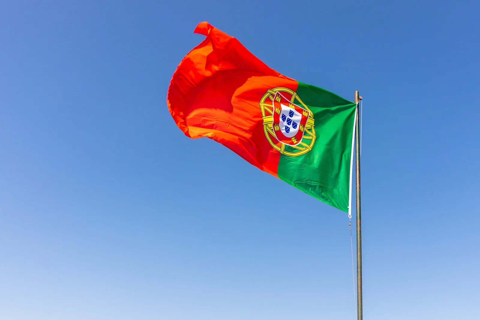 Bandeira de Portugal tremulando contra um céu azul