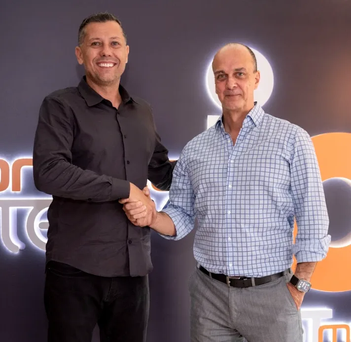 Rafael Galasso gesticulando no palco de um evento da TEG, em frente ao logo iluminado
