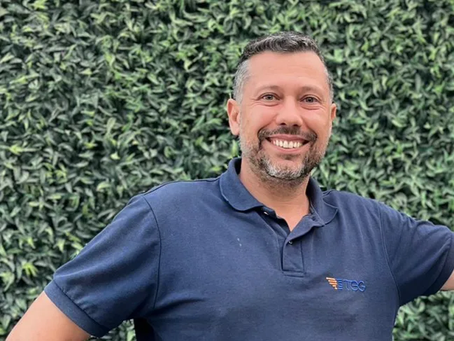 Rafael Galasso sorrindo em frente a um painel de plantas
